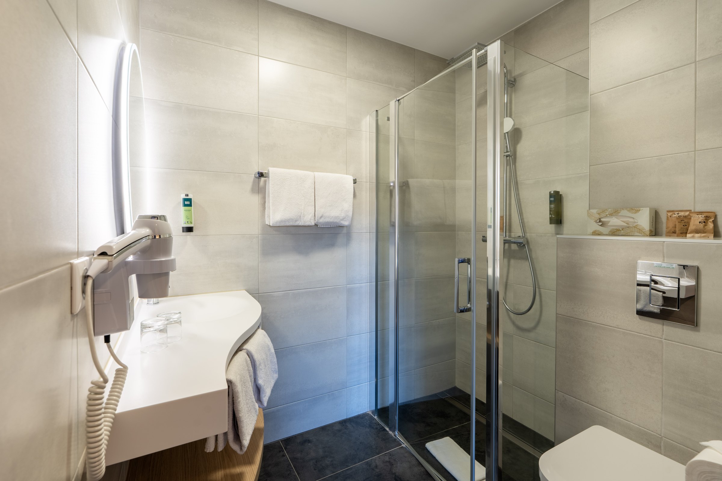 Bathroom with glass shower, washbasin and towels