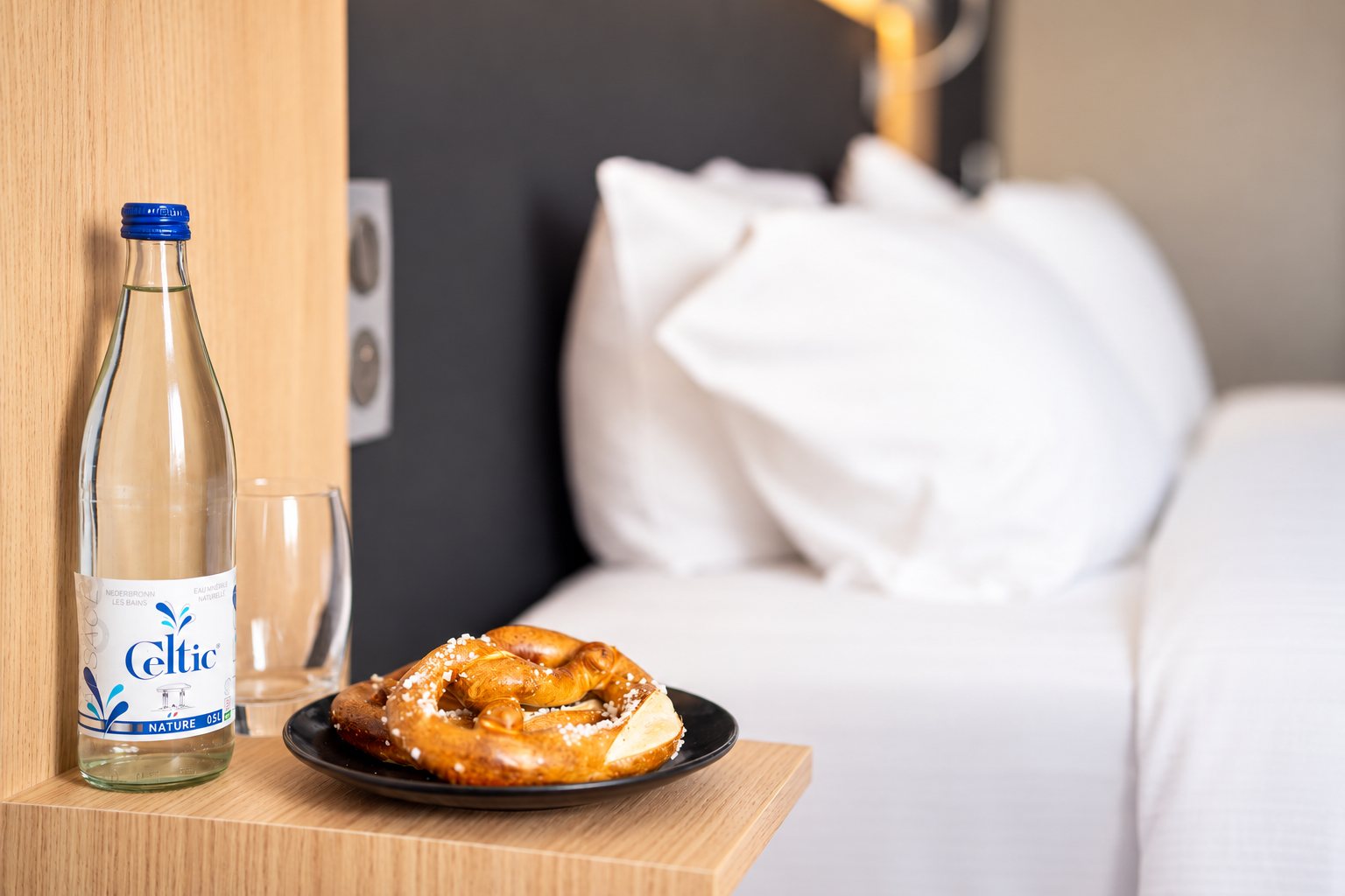 Bottle of water and a pretzel on the bedside table of a double room