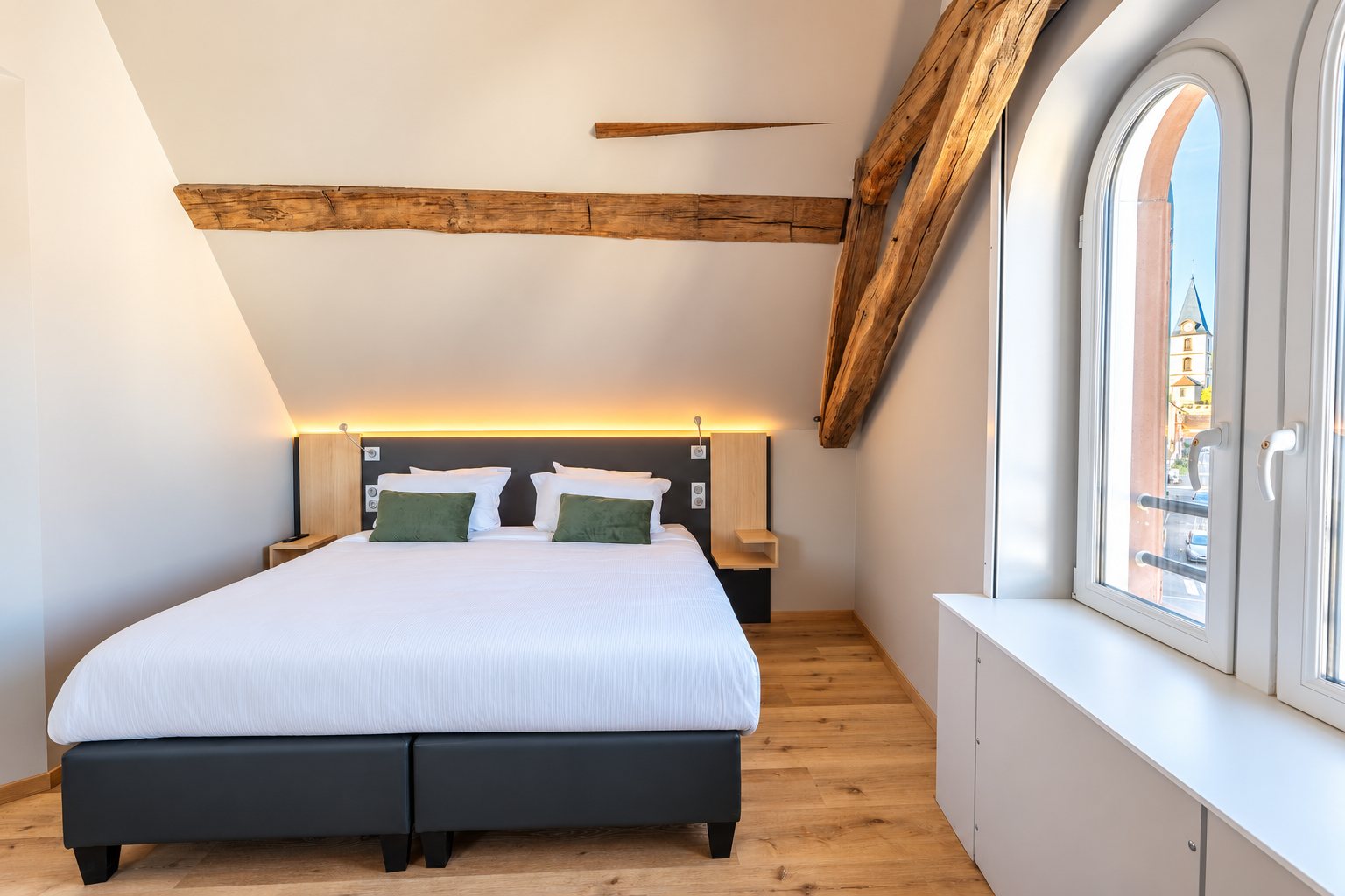 Large bed under the eaves and arched windows of the Signature junior suite