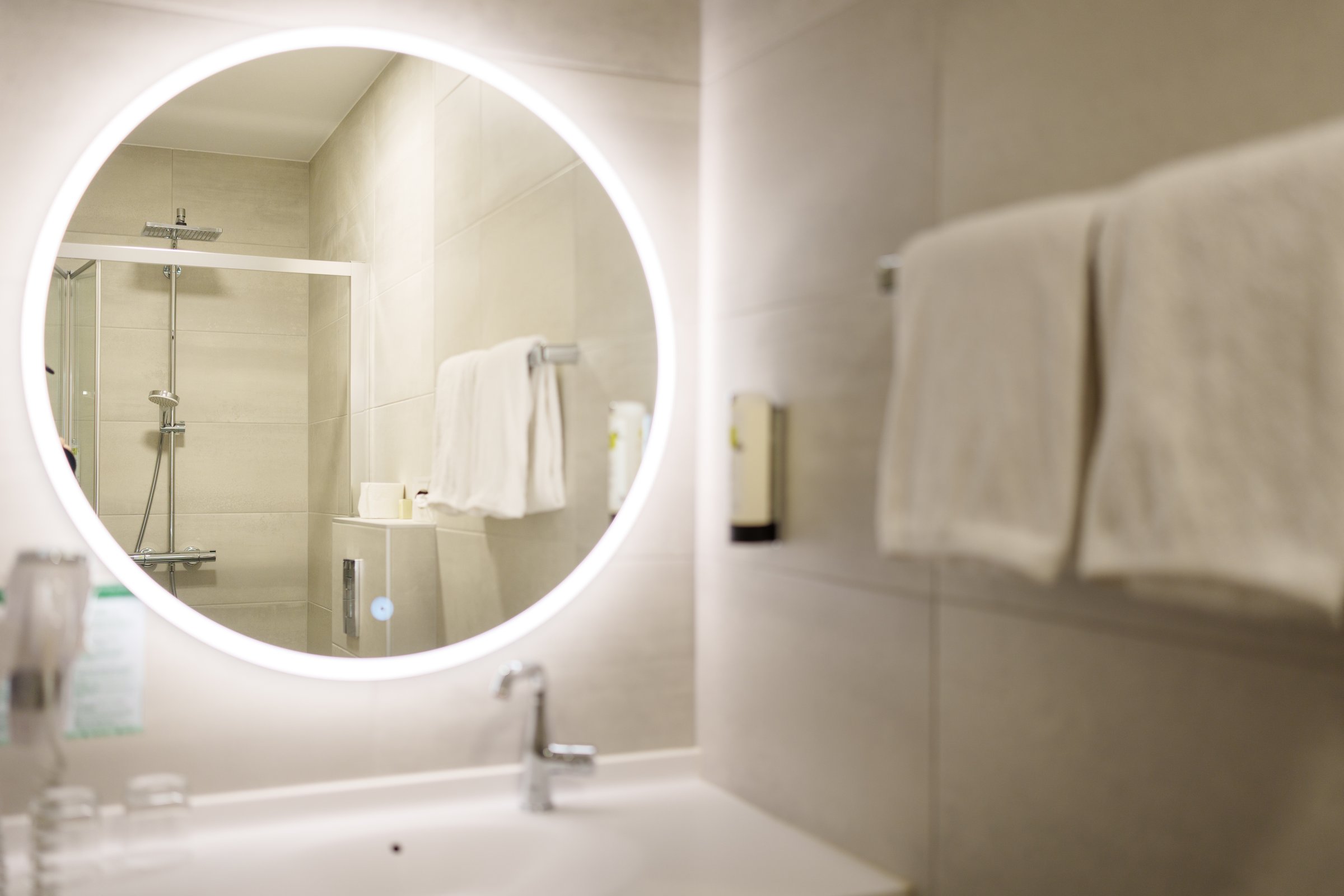 Beleuchteter Spiegel mit Blick auf die ebenerdige Dusche im modernen Badezimmer